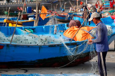 Balıkçılar balık ağlarını onarıyor. Dua hangarını asın. Vung Tau. Vietnam. 