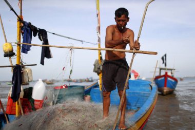 Balıkçılar balık ağlarını onarıyor. Dua hangarını asın. Vung Tau. Vietnam. 