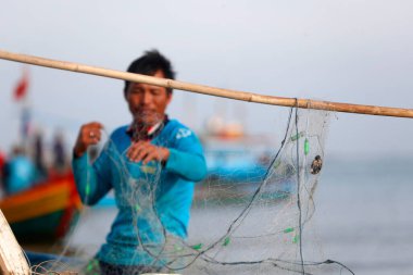 Balıkçılar balık ağlarını onarıyor. Dua hangarını asın. Vung Tau. Vietnam. 