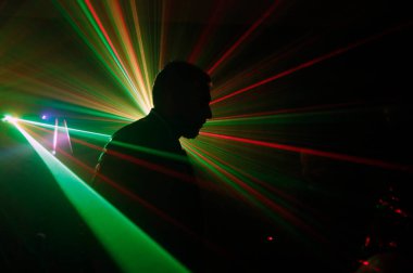 Diskoda lazer ışıklarıyla dans eden bir adamın silüeti..