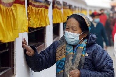 Tibetli bir kadın Bodhnath Stupa çevresinde dua tekeriyle hacca gidiyor.. 