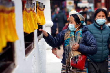 Tibetli bir kadın Bodhnath Stupa çevresinde dua tekeriyle hacca gidiyor.. 