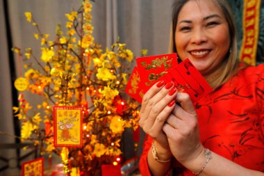 Çin ve Vietnam 'ın yeni yıl kutlamaları için kırmızı zarflı Asyalı kadın. Kırmızı renk iyi şansın sembolüdür. Evde din var.. 