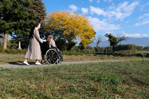 Ziyaret Manastırı. Bahçe. Tekerlekli sandalyedeki yaşlı rahibe. Fransa. 