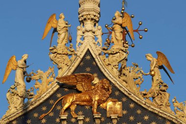 San Marco Bazilikası. Venedik ve Aziz 'in sembolü olan Kanatlı Aslan' ın üstündeki meleklerle Aziz Mark. Altın kanatlı aslan heykeli ve bazilika cephesinde melekler. Venedik. İtalya. 