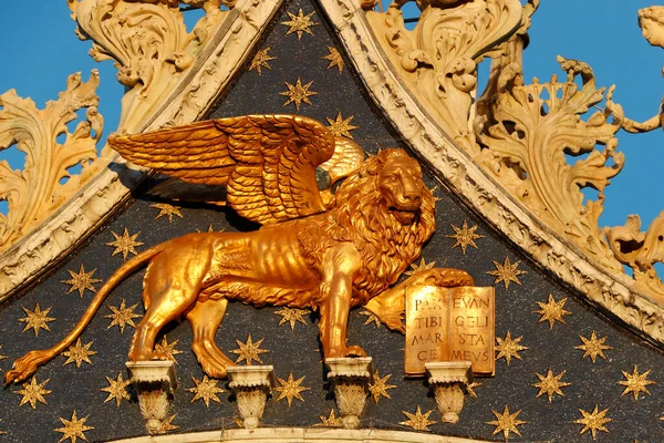 Lion of Saint Mark and church.  Basilica San Marco.   Golden winged Lion, symbol of St. Mark, patron saint of Venice.  Venice. Italy.