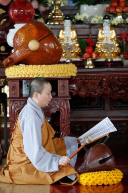 Tapınakta Budist ayini. Monk tahtadan bir balıkla (perküsyon aleti) oynuyor. Ho Chi Minh şehri. Vietnam. 