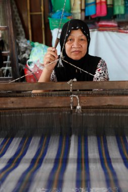 Traditional hand loom.  Local muslim woman diligently weaving colourful scarves.  Chau Doc. Vietnam. 