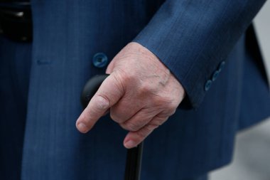 Yaşlı adamın eli bastona dayanıyor. Yakın plan..