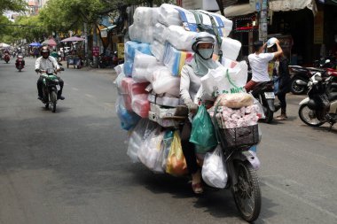 Woman driving a motorbike with big charge on Saigon Street. Ho Chi Minh City. Vietnam. 