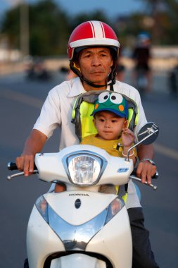 Man with his son  driving a motorbike on Cai Be bridge.  Vietnam. 
