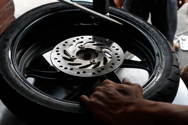 Motosiklet tamircisi mekanik atölyesinde eski bir lastiği söküyor. Ho Chi Minh Şehri. Vietnam. 