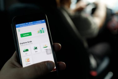 A man holds up a smartphone showing the Grab app. Ho Chi Minh city. Vietnam. 