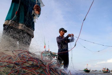 Güney Çin Denizi. Balıkçılar balıkçı ağları üzerinde çalışıyor