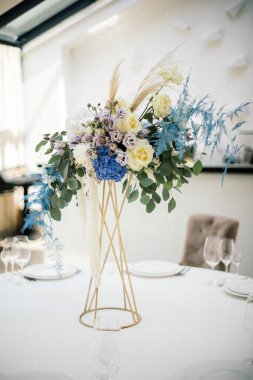 Düğün masasındaki vazonun içindeki çiçeklerin güneşli resmi.