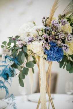 Çiçek kompozisyonu düğün masasında.