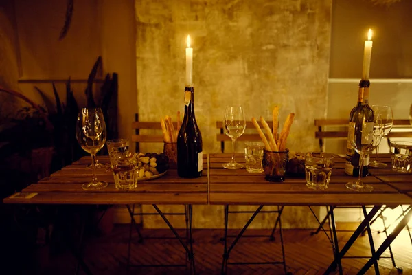 Candles in bottles with wine and dinner