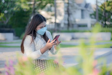 Genç Asyalı kadın dışarıda konuşmak ve mesajlaşmak için telefon kullanıyor. İş ve iletişim kavramı