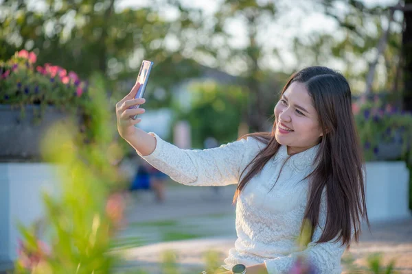 Bahçede kulaklıklı gülümseyen kadın akıllı telefon, eğlence ve yaşam tarzı konseptine odaklanıyor.
