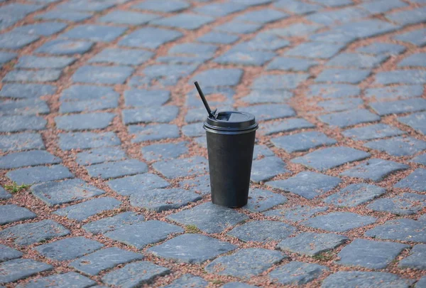 Una Taza Plástico Negro Con Una Paja Encuentra Los Adoquines — Foto de Stock