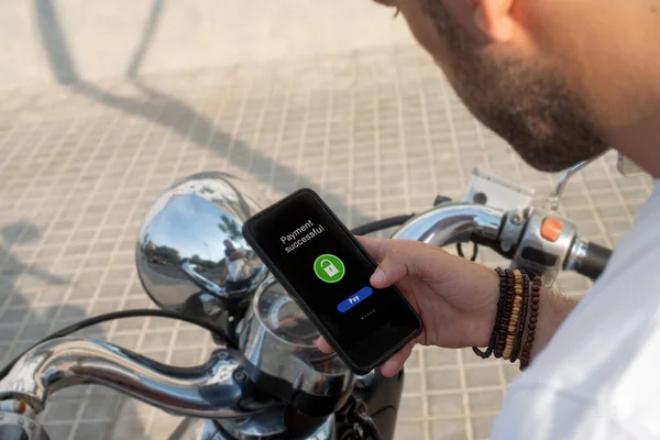 Adam motosiklet kirasını cep telefonuyla ödüyor.