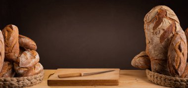 Karatahta kahverengi pankartta fotokopi alanı olan bir sepet zanaatkâr ekmek. 