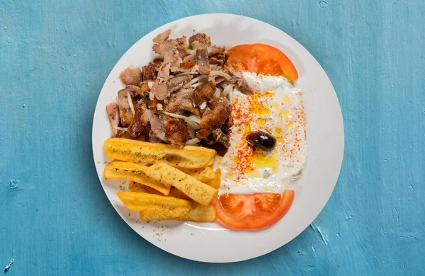 Greek dish of Gyro with lamb meat with onion accompanied by French fries and Tzaziki sauce with tomato