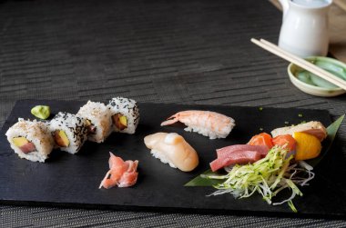 Siyah masa örtüsü üzerinde suşi çeşitleri olan siyah taş bir masa üzerinde fotokopi alanı 