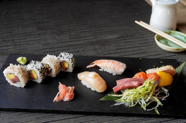Black stone table with varieties of Sushi on black tablecloth with copy space on top 