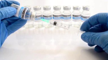 gloved hands fill syringe from  vial with monkeypox vaccine close up