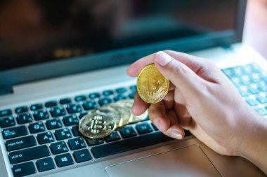 İşadamının elinde dizüstü bilgisayarda altın bir Bitcoin var. Bitcoin ile para kazanmak, dijital para birimi para yatırım konsepti, engelleme zinciri transferi.