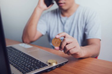Altın Bitcoin ve akıllı telefonu dizüstü bilgisayarda tutan bir iş adamı. Bitcoin ile para kazanmak, dijital para birimi para yatırım konsepti, engelleme zinciri transferi.