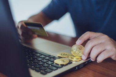Adam bilgisayar, kripto para birimi modern finansal konsept kullanırken küçük alışveriş arabasına bitcoin koyuyor..