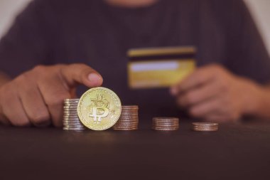 Elinde altın Bitcoin ve kredi kartı olan bir adam. Bitcoin ile para kazanmak, dijital para birimi para yatırım konsepti, engelleme zinciri transferi.