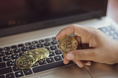 İşadamının elinde dizüstü bilgisayarda altın bir Bitcoin var. Bitcoin ile para kazanmak, dijital para birimi para yatırım konsepti, engelleme zinciri transferi.