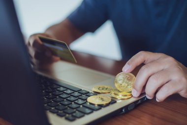 Adam bilgisayar, kripto para birimi modern finansal konsept kullanırken küçük alışveriş arabasına bitcoin koyuyor..