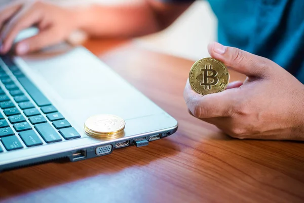 İşadamının elinde dizüstü bilgisayarda altın bir Bitcoin var. Bitcoin ile para kazanmak, dijital para birimi para yatırım konsepti, engelleme zinciri transferi.