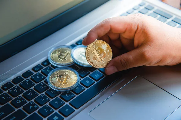 İşadamının elinde dizüstü bilgisayarda altın bir Bitcoin var. Bitcoin ile para kazanmak, dijital para birimi para yatırım konsepti, engelleme zinciri transferi.