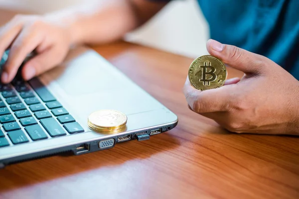 İşadamının elinde dizüstü bilgisayarda altın bir Bitcoin var. Bitcoin ile para kazanmak, dijital para birimi para yatırım konsepti, engelleme zinciri transferi.