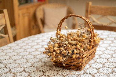 Masanın üzerinde kurumuş gül çiçekleri olan sepet.