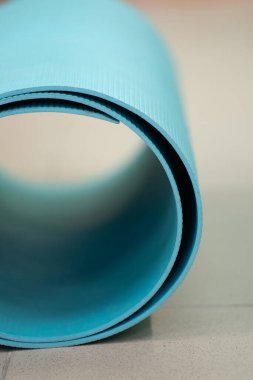 Turkuaz yoga ve pilates minderi spor salonunda yerde yatıyor.