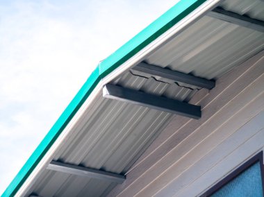 Düşük açı, çatı köşesi, metal kaplama çatı. Sırt ve saf çelik. Krem renkli yapay ahşap.