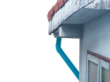 Düşük açılı manzara, paslanmaz çelik yağmur olukları ve mavi PVC boruları olan çatı köşesi..