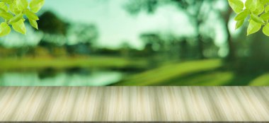 Ahşap masa yüzeyi ve önde yapraklar, halka açık bahçede bulanık arka plan, tatil sabahı gölgeler, ağaçlar ve gölgeler..