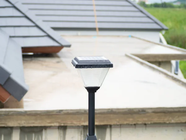 Close-up shot, outdoor solar light mounted on a wall. For homes, buildings. Future technology, clean energy, safe, less pollution. Behind is blurry houses under construction.