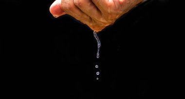 The human hand holds water with his hands and the water drops below. The purity of the water.The benefits of water. conditions of drought and natural disasters.