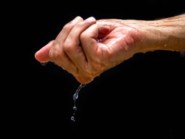 The human hand holds water with his hands and the water drops below. The purity of the water.The benefits of water. conditions of drought and natural disasters.