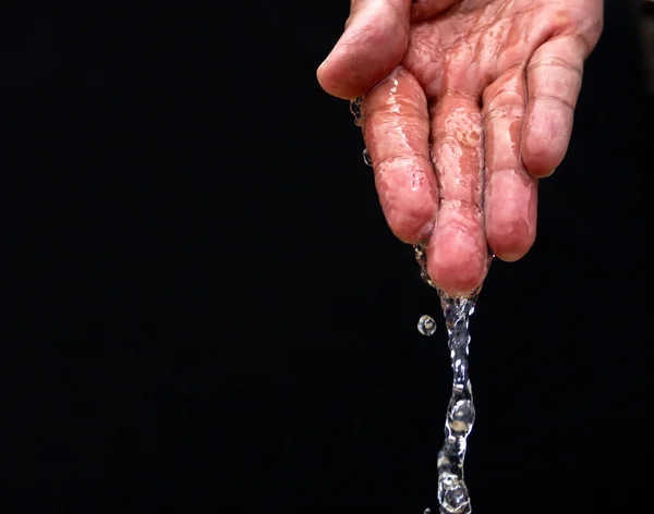 Water flows on the palm of the hand down below. The purity of the water.The benefits of water. conditions of drought and natural disasters.