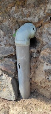 Endonezya 'nın Cikancung bölgesinde bir duvardaki delinmiş ve çatlak bir kanalizasyon borusunun soyut odaklanmış fotoğrafı.