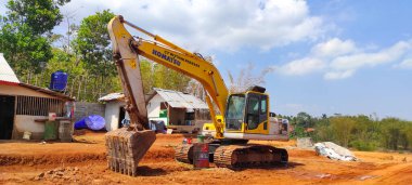 Cicalengka, Batı Java, Endonezya - 20 Ekim 2021: Turuncu renkli kazı aracı sıcak bir günde, Endonezya 'da karayı düzleştirmek için kullanılır 